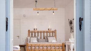 A bedroom with a wooden bed frame, bedside tables, and a hanging light fixture. - Aqua Naxos Apartments and Suites (Naxos)