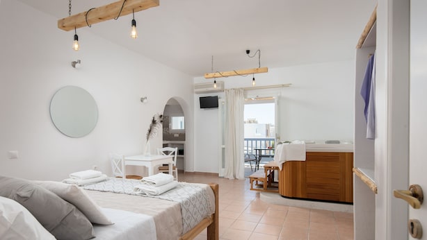 A modern bedroom with a bed, a desk, and a bathroom. - Aqua Naxos Apartments and Suites (Naxos)