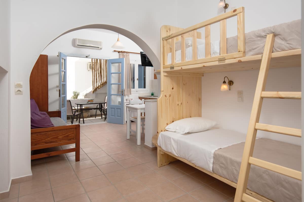 Ein kleines Zimmer mit Stockbetten, einem Schreibtisch und einem Stuhl.