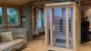 A room with a wooden floor, a glass-enclosed fireplace, a stone wall, and a wooden ceiling. - Meagill Farmhouse, hot Tub, bbq hut (Otley)