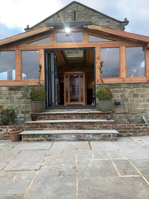 A stone building with a wooden front, large windows, and a door. - Meagill Farmhouse, hot Tub, bbq hut (Otley)