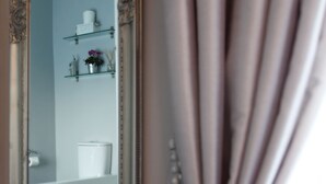Un baño con una bañera blanca, un inodoro y un estante con artículos de aseo.