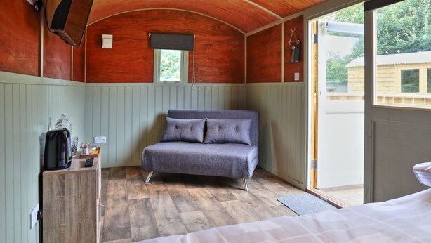 Un dormitorio acogedor con una cama, un sofá cama, un armario de madera y una ventana.