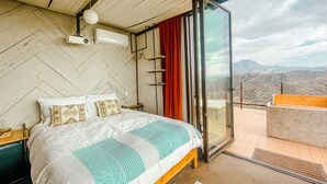 A bedroom with a large bed, a sliding glass door leading to a balcony, and a view of the mountains. - Native Residence (Playas de Rosarito)