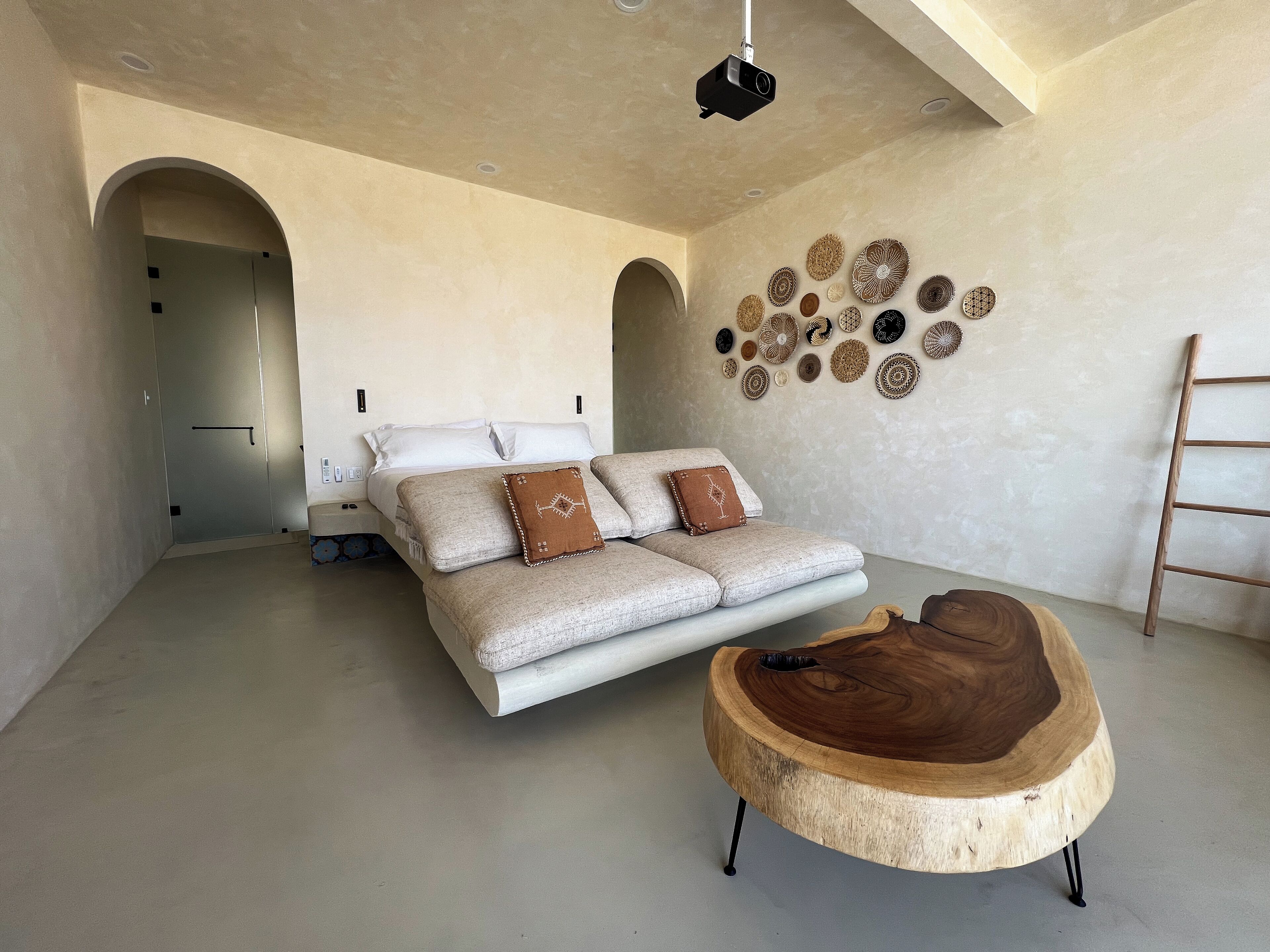 A spacious bedroom with a large bed, a wooden coffee table, and a wall decorated with woven baskets.