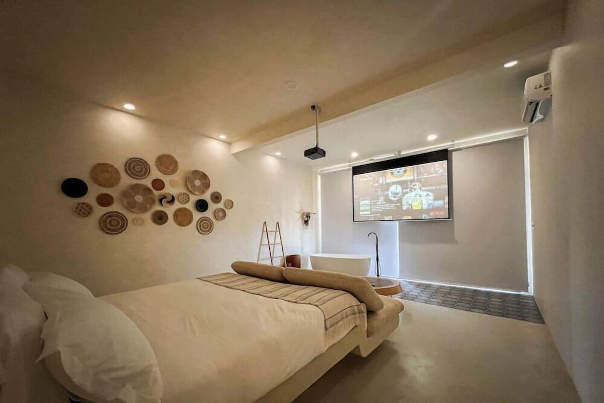 A modern bedroom with a bed, wall decor, a TV, and a ladder.