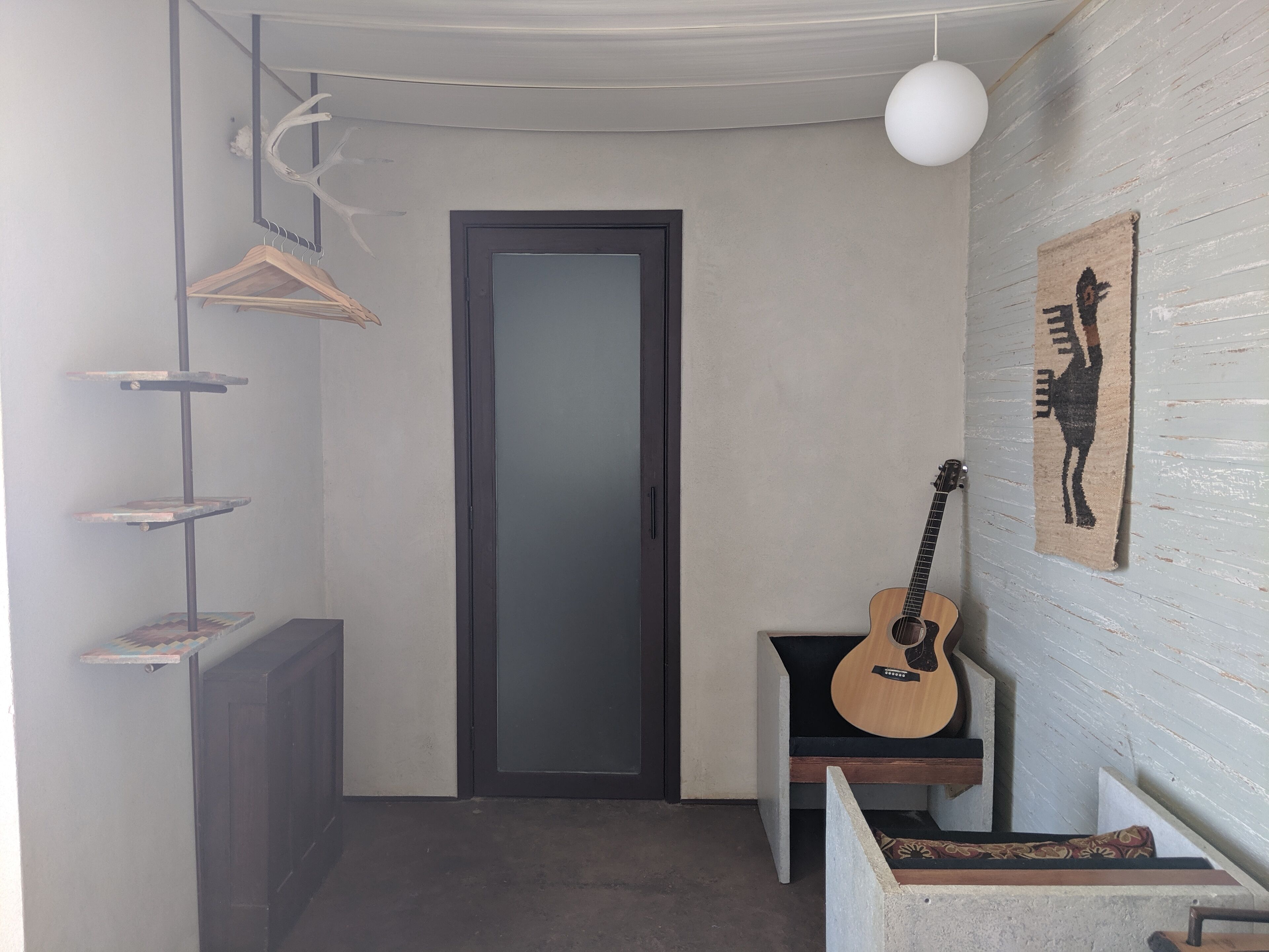 Ein Flur mit einer Gitarre, einer Tür und einem Wandteppich.