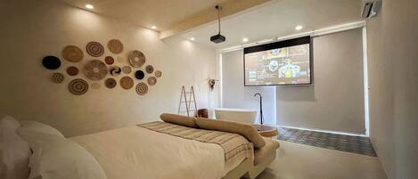 A modern bedroom with a large bed, a wall-mounted TV, and a ceiling light.