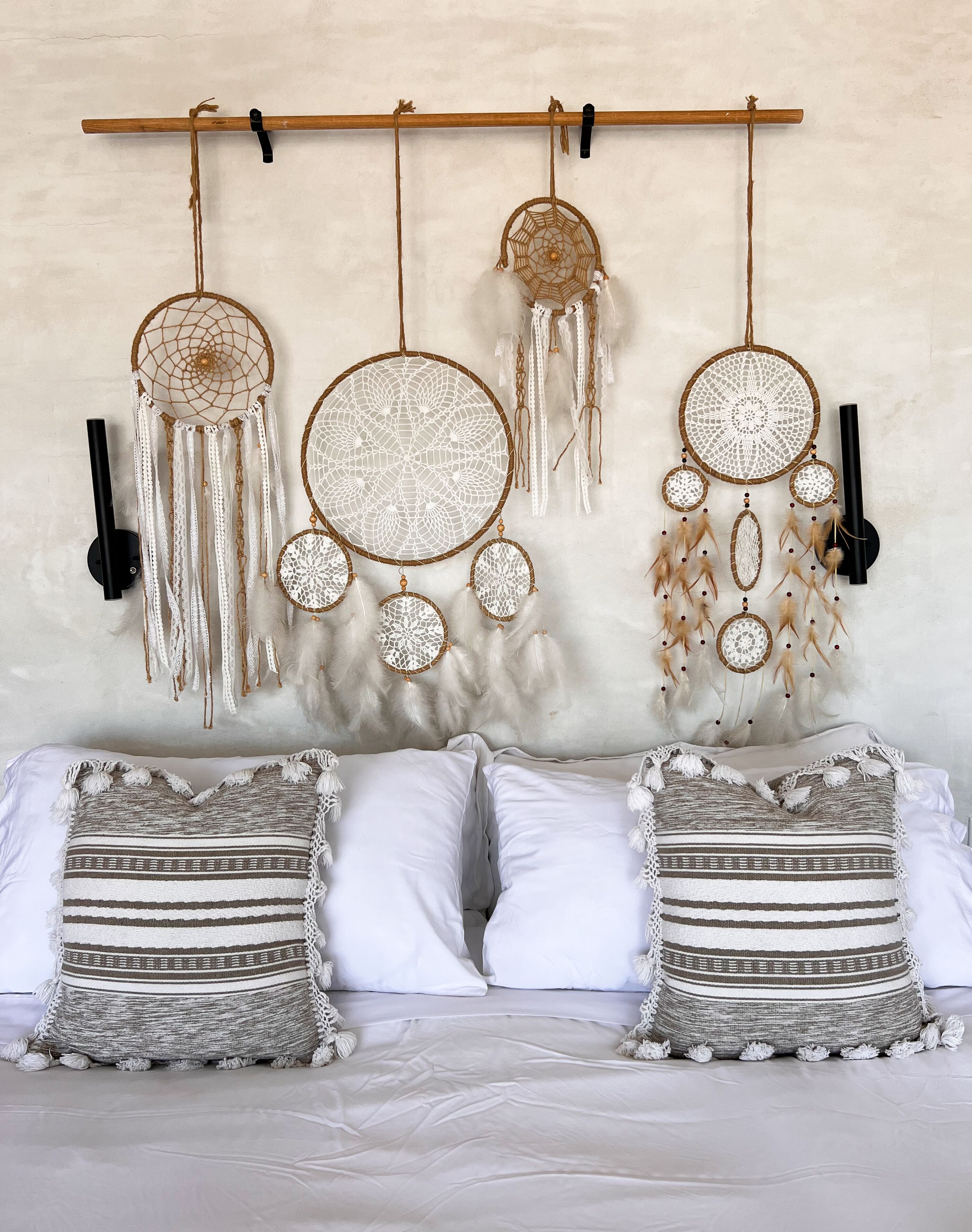 A bed with two pillows and a wall-mounted dreamcatcher.