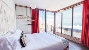 Un dormitorio moderno con una cama grande, vista a la playa y un balcón.