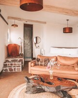 Quarto aconchegante com escadaria de pedra, banheira de cobre, mesa de centro de madeira e sofá marrom com um vaso decorativo.