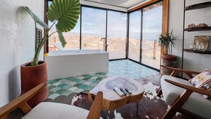 A modern bathroom with a bathtub, large windows, and a view of a mountainous landscape. - Native Residence (Playas de Rosarito)