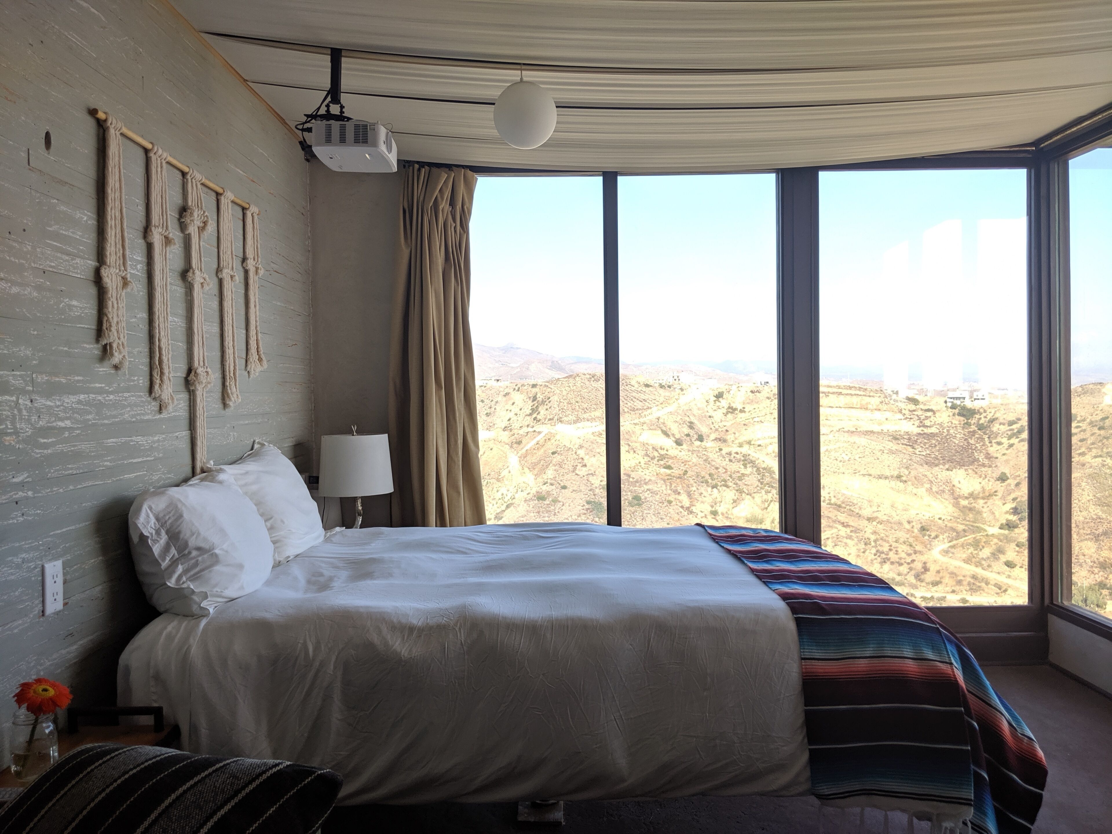 Une chambre à coucher avec un lit, une lampe, un projecteur et une vue sur un paysage montagneux.
