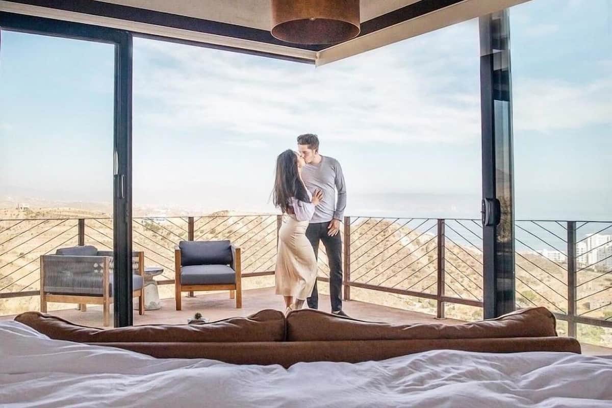 A bedroom with a large bed, a chair, and a view of the landscape.