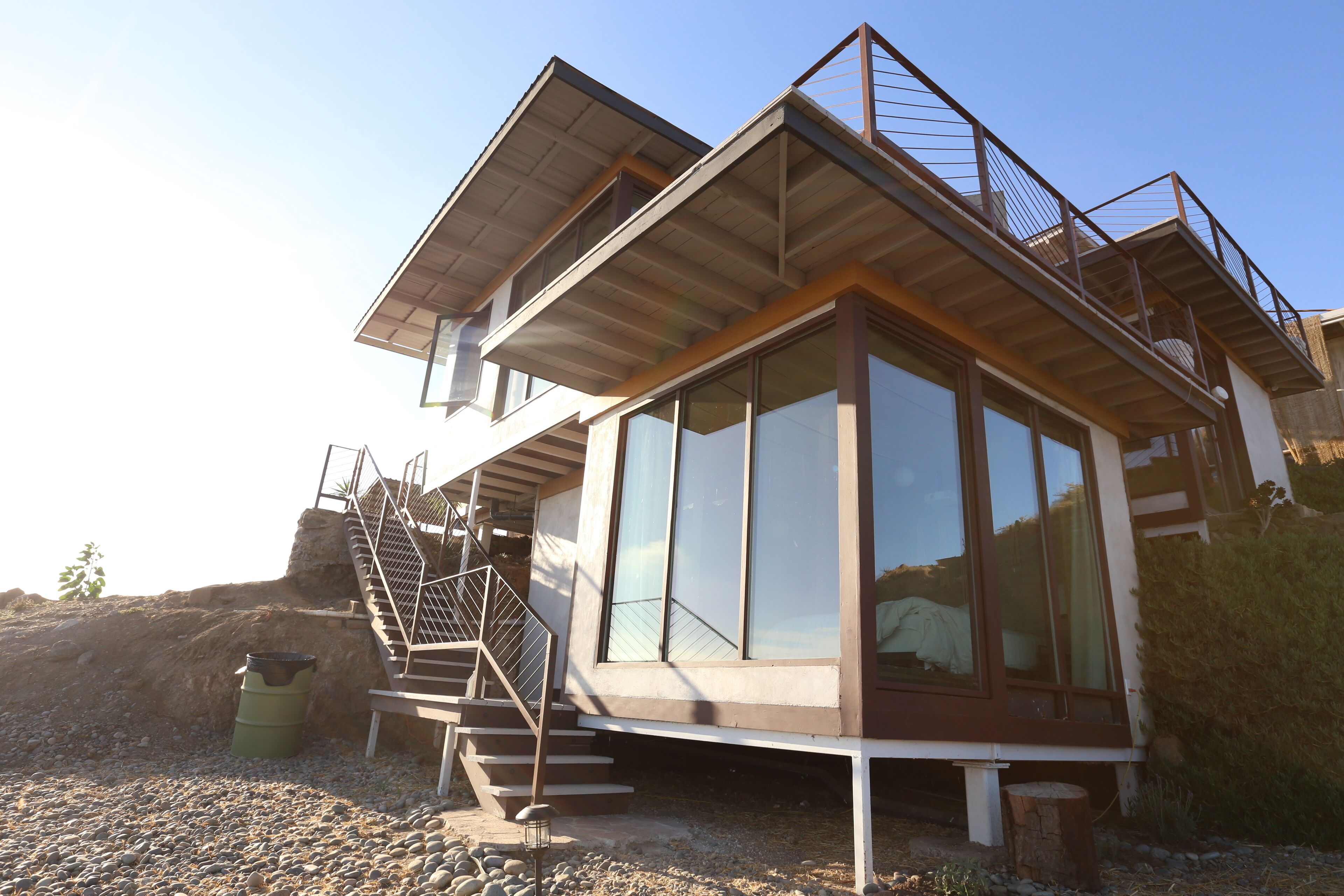 A modern multi-level house with a balcony, large windows, and a staircase.