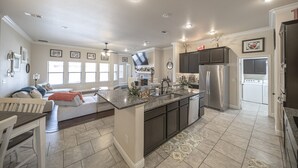 A spacious kitchen with a central island, stainless steel appliances, and a dining area with a sofa and table. - Enormous house with new backyard (Midland)