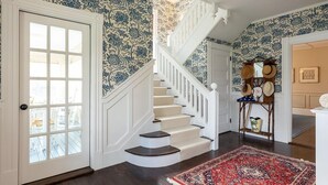 A staircase with a white railing, a patterned wall, and a red rug. - MASSIVE Oceanfront Dark Harbor Home on ISLESBORO (Islesboro)