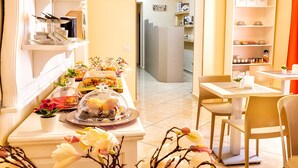 A hotel room with a dining area featuring a buffet table, a small seating area with a table and chairs, and a bookshelf with decorative items. - Re Diego (Naples)