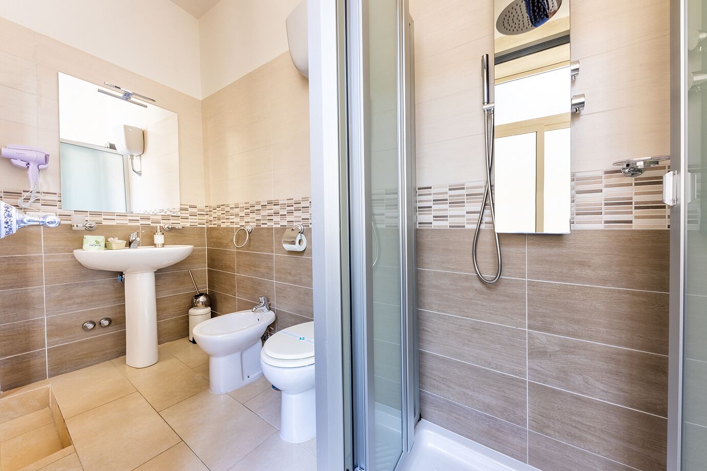 Une salle de bain moderne avec une douche à parois de verre, un lavabo, un bidet et des toilettes.