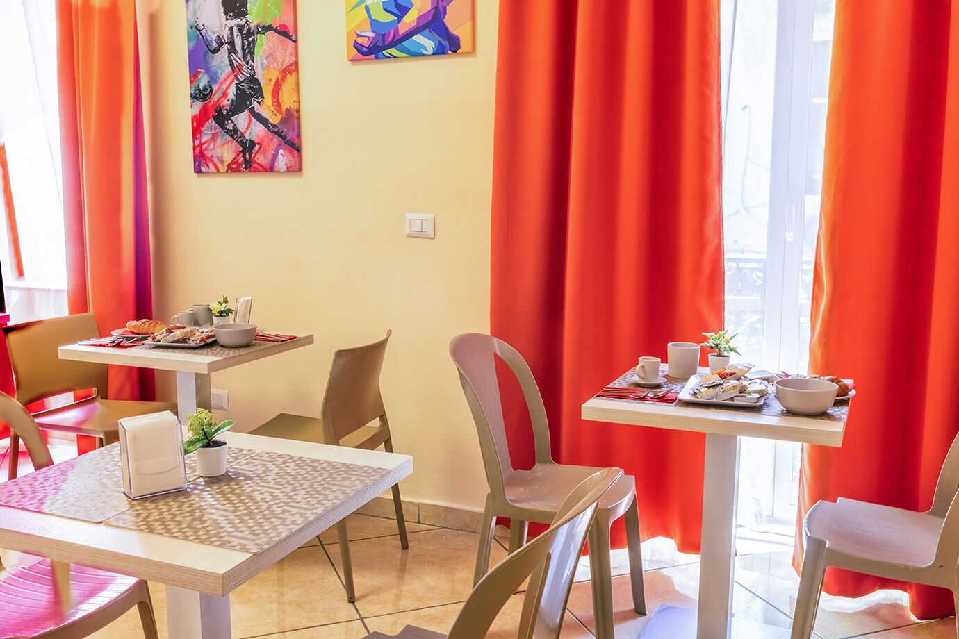 A dining area with tables set for breakfast, featuring a mix of chairs and a bench.
