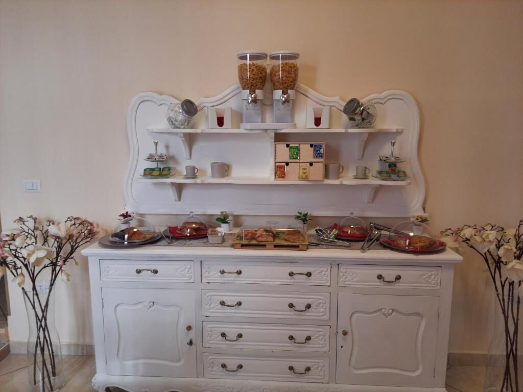 A white buffet setup with multiple serving stations, including a coffee dispenser and a variety of food items displayed on trays.