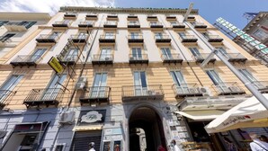 A multi-story building with balconies, a storefront, and a clear sky. - Re Diego (Naples)