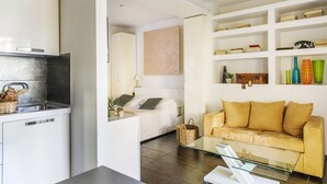 Un espacio habitable moderno con cocina, una cama, un sofá y una mesa de centro de vidrio.