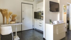 Una cocina moderna con gabinetes blancos, un microondas y un televisor de pantalla plana montado en la pared.