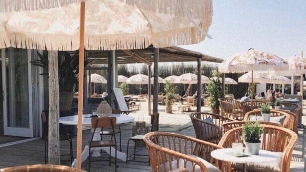 An outdoor seating area with wicker chairs and tables, covered by large umbrellas. - Salty Beach House near Beach and city centre (Noordwijk)