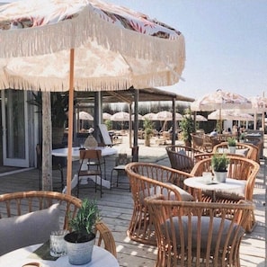 An outdoor seating area with wicker chairs and tables, covered by large umbrellas. - Salty Beach House near Beach and city centre (Noordwijk)
