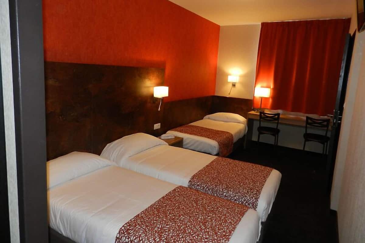 Habitación de hotel con dos camas, un escritorio y una silla.