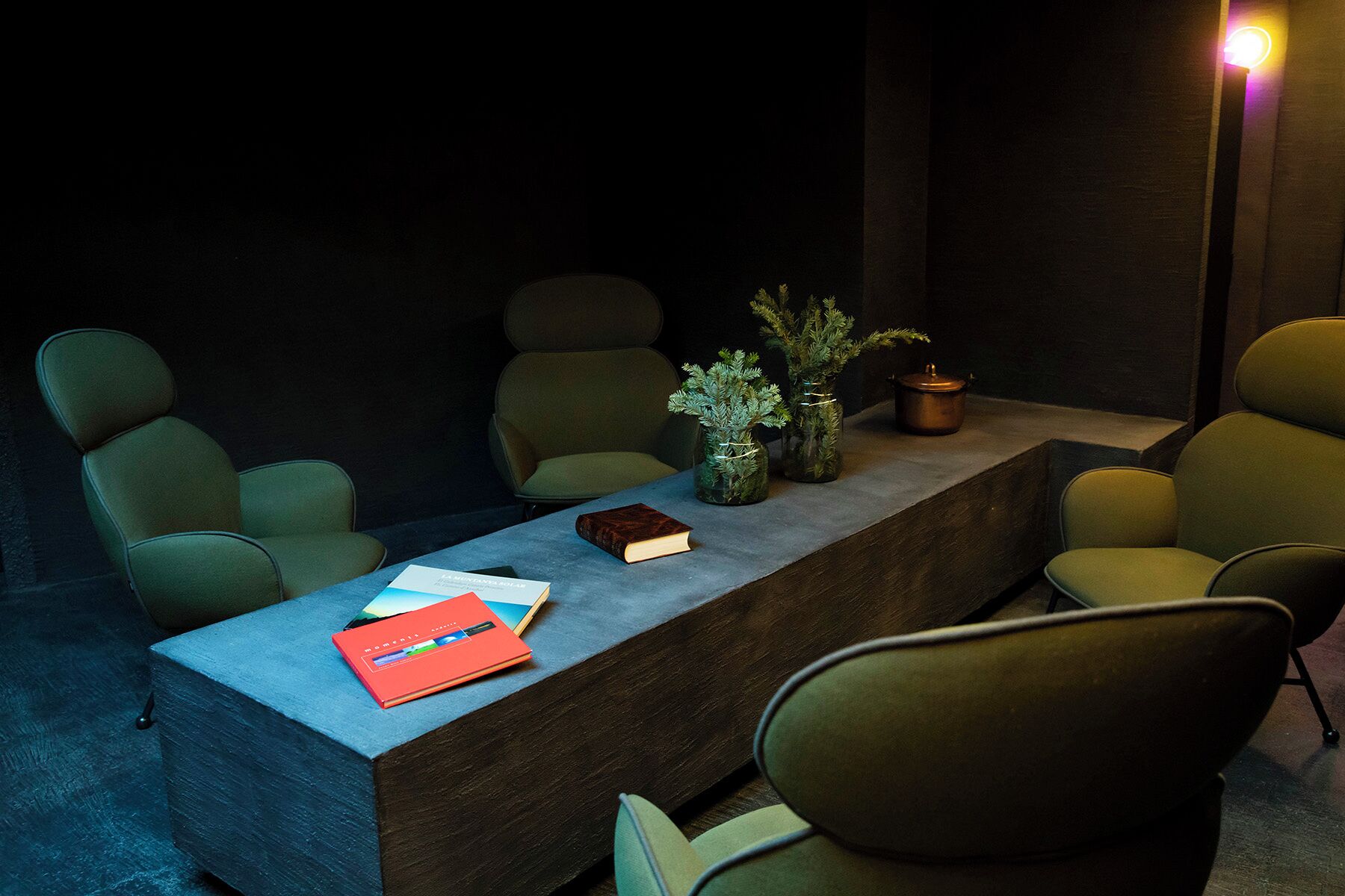 A conference room with a long table, several chairs, and a few decorative items including books and vases.