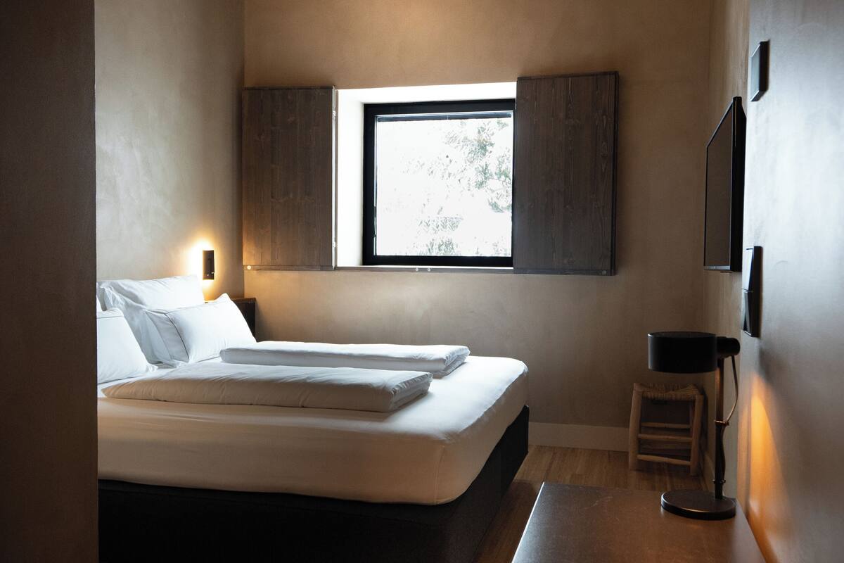 Una camera da letto con un letto, un comodino, una sedia e una finestra vista.