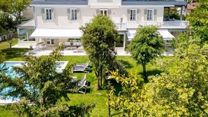 A modern two-story house with a swimming pool, outdoor seating, and lush greenery. - Villa Guidi 10, Emma Villas (Cervia)