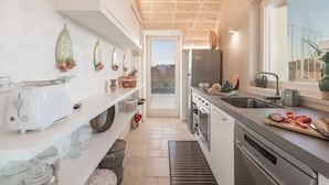 A modern kitchen with white cabinetry, a stainless steel refrigerator, and a large window providing a view of the outdoors. - Villa Gialonia 8+2, Emma Villas (Salve)