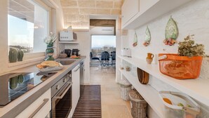 A modern kitchen with a central island, built-in appliances, and a view to the dining area. - Villa Gialonia 8+2, Emma Villas (Salve)