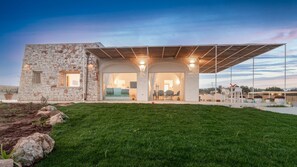A modern house with a stone facade, large glass doors, and a covered outdoor area.