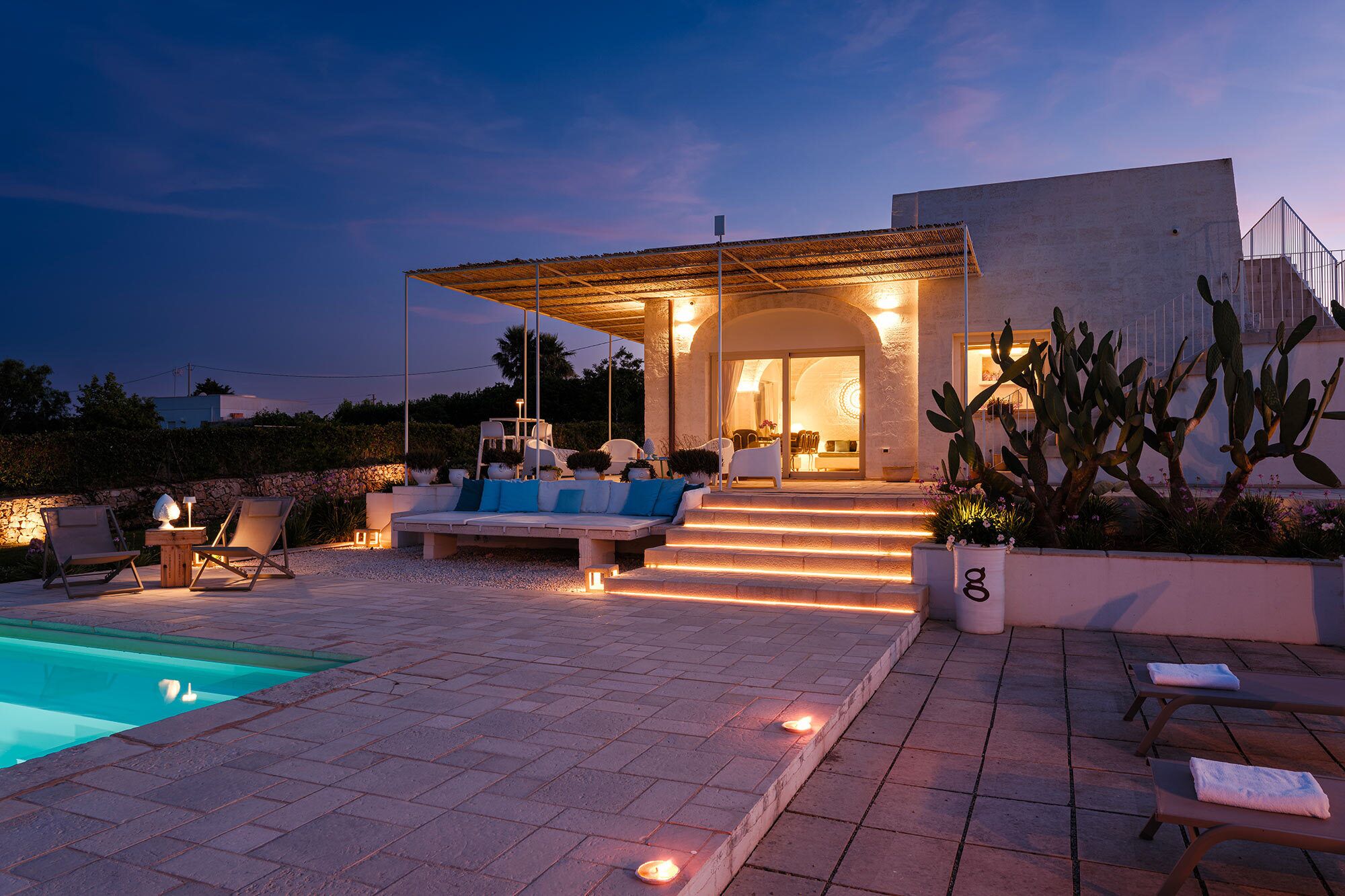 A modern outdoor living area with a pool, seating, and a covered patio.