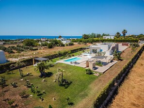 A residential property with a swimming pool, garden, and a view of the sea.
