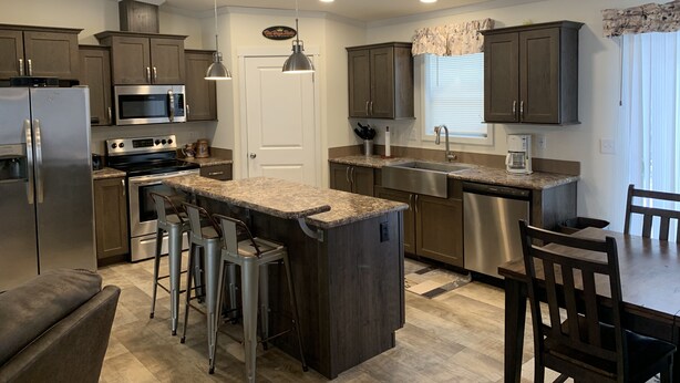 A modern kitchen with granite countertops, stainless steel appliances, and bar stools. - Hideout Haven (Baraboo)