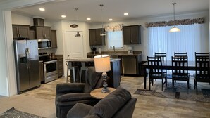 A modern kitchen with stainless steel appliances, a dining area with a table and chairs, and a cozy seating area with a sofa and armchairs. - Hideout Haven (Baraboo)