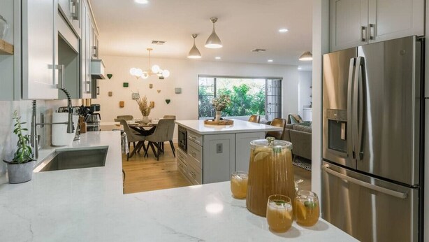 A modern kitchen with a stainless steel refrigerator, a dining area with a table and chairs, and a large window providing natural light. - Luxury 5BR Old Town Villa with Heated Pool & Games (Scottsdale)