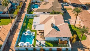 A modern house with a swimming pool, a covered patio, and a well-maintained lawn. - Luxury 5BR Old Town Villa with Heated Pool & Games (Scottsdale)