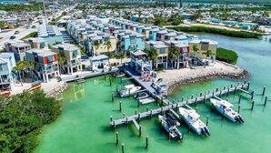 Un port de plaisance avec des bateaux amarrés, une jetée et une rangée de bâtiments aux couleurs vives.
