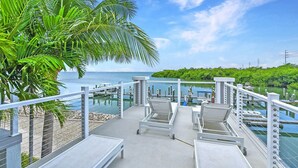 Une terrasse avec des chaises longues donnant sur une marina et sur l’eau.