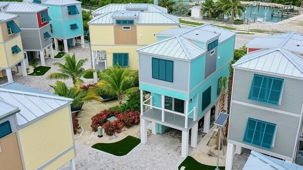 Une zone résidentielle côtière avec des maisons aux couleurs vives, une plage et un port de plaisance.