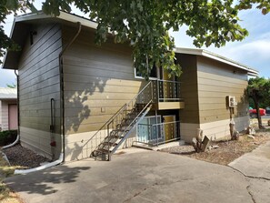 Two-story building with a metal staircase and a small tree in the surrounding area.