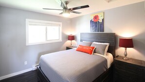 A bedroom with a bed, a ceiling fan, a window, and two bedside lamps. - Unit B Minimalist Living, Simply...Perfect! (Kalispell)
