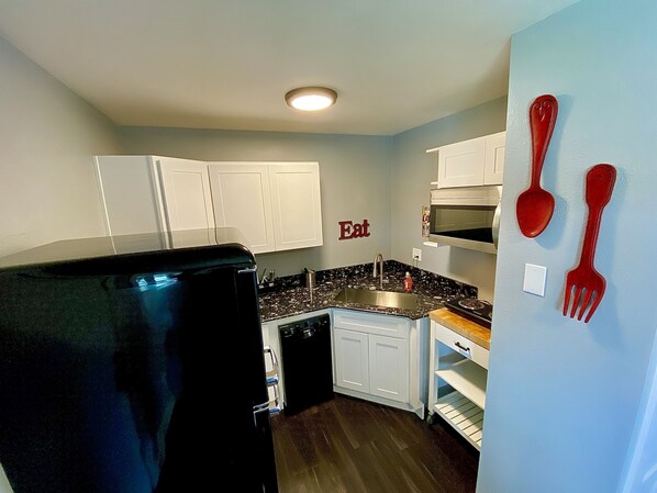 Enjoy cooking in this kitchen with a stainless steel sink and microwave, and a convenient 'Eat' sign on the wall.