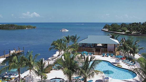 Un resort con piscina, sillas de descanso y vistas al océano.